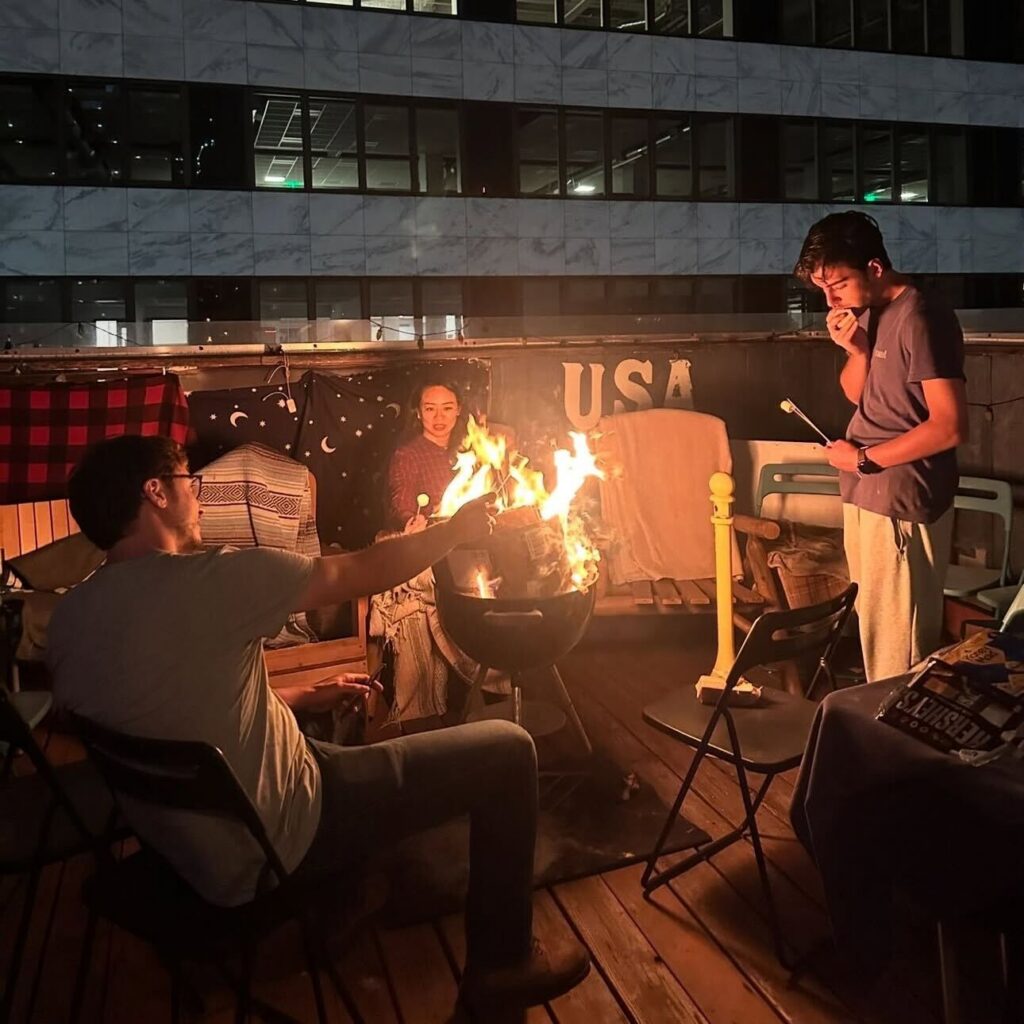 Hostel guests roasting marshmallows around a rooftop fire pit at Pacific Beach nightlife at an International Travelers House location.